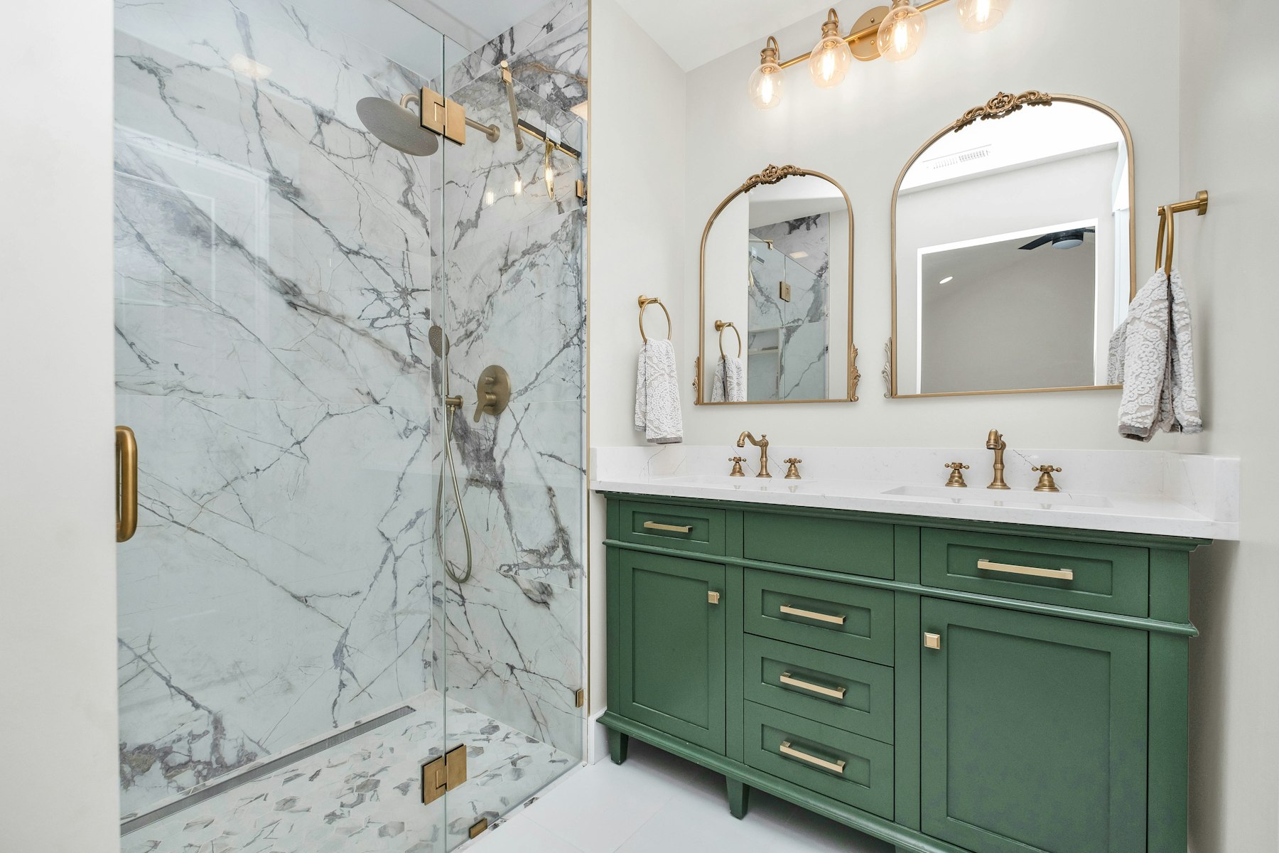 A walk-in shower finished in marble with a glass panel