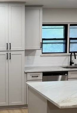 Renovated kitchen with white shaker cabinets, subway-tile backsplash and a marble waterfall island, part of a 1981 North Austin whole-home transformation